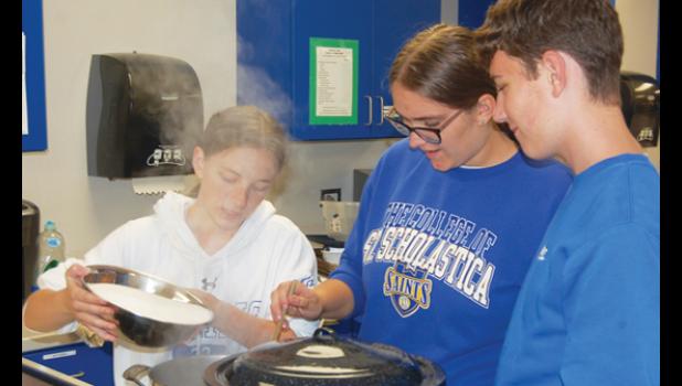 Mascot photo by Scott Thoma Jaelin Anderson, left, pours sugar into a pot of boiling grape juice and sure-gel as Samantha Landrus and Riley Wambeke look on. The mixture then must boil for a full minute.
