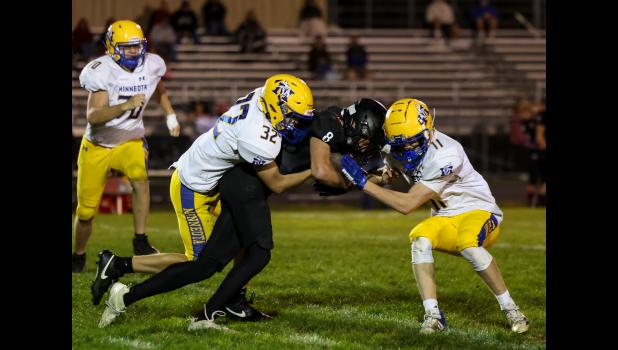 Minneota's Evan Jerzak (32), left, and Owen Myrvik (11) stop Lac qui Parle Valley quarterback Gavin Meyer after a short run Friday night in Madison. 