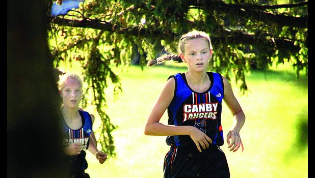 Staff Photo by Byron Higgin. Grace Drietz ran through the trees with teammate McKenzie Ruether right behind her.