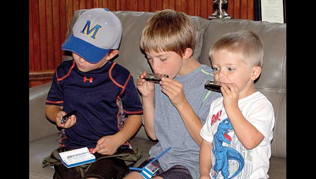 Staff photo by Hannah Buysse. Harmon and Nolan Van Keulen and Bennet Myhre (left to right) got their harmonicas and tried them out right away. Getting the kids involved was a good way to drive home the kind of music played by Smithson’s group.