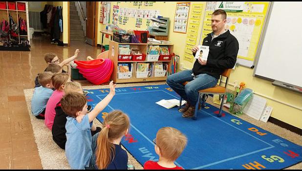 Special photo. The St. Edward kindergarten class is learning about needs, wants, and saving money through Junior Achievement with volunteer Seth Myhre.