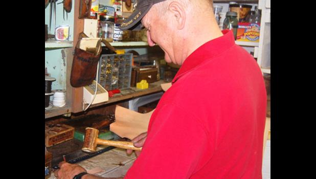 Staff photo by Scott Thoma. Dan Markell works on a leather handle for one of the trunks he is restoring.