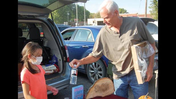 Mascot photo by Scott Thoma Emily Lasnetski of Ivanhoe accepts a complimentary bottle of water from Kevin Anundson during the Farmers Market last Thursday.