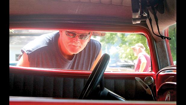 Staff photo by Scott Thoma. Don Kurtenbach of Marshall peers in the window of a 1932 Ford Coupe showed by Gary Sorkness of Marietta. Sorkness' vehicle was the People's Choice winner.