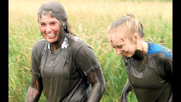 Staff photo by Scott Thoma. Payton Boerboom and her college roommate Reegyn Powers after crawling under the covered mud pit.