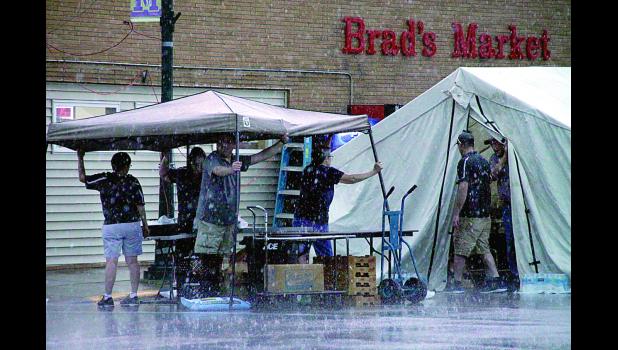 Staff Photo by Byron Higgin. Raindrops fell on the Brad's Market tent as workers held down the awning during the rain storm.