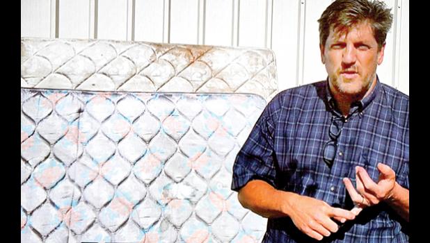 Special photo. Environmental Director Roger Schroeder in front of a couple of mattresses at the recycling center.