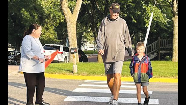 Contributed photo Elementary Principal Jen Mahan-Deitte holds up traffic as a student and his father cross the street.