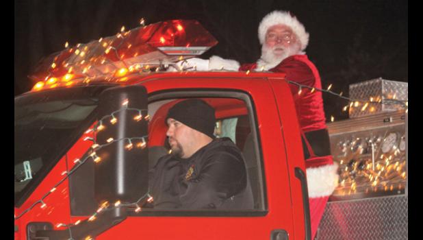 Staff photo by Scott Thoma. The Minneota fire trucks paraded through town Friday night with Santa Claus aboard one of the decorated trucks. Santa Claus waved and shouted "Merry Christmas" to the many children, parents and grandparents standing on the sidewalks.