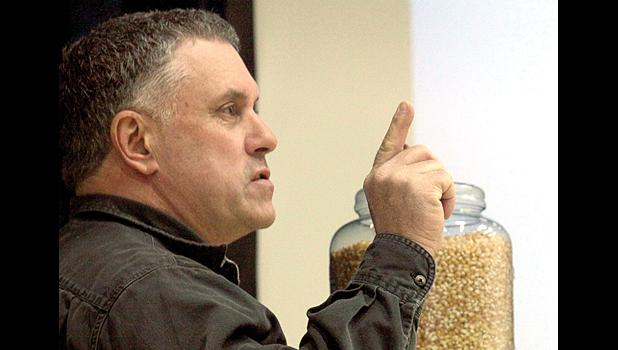 Staff Photo by Byron Higgin. Gene Stengel, with a jar of corn behind him, resembling a grain bin, made his point clear — safety first.