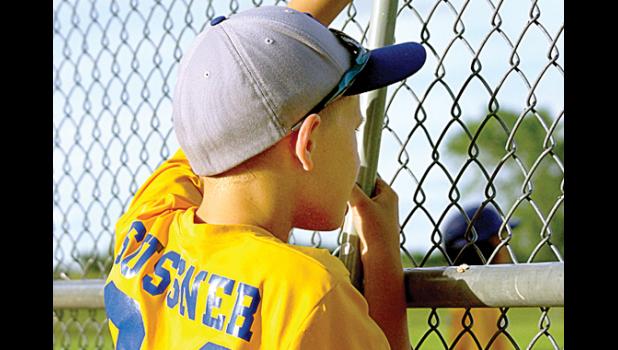 Photo for the Mascot by Sue Jacobson. Meanwhile, watching the action from behind the fence in the dugout area was Tristan Sussner of Minneota.