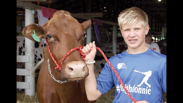 Staff Photo by Byron Higgin. Zack Fier and his grand champion dairy cow.