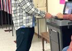 Eli Gruenes, a senior at Minneota High School, turned 18 in September and was eligible to vote for the first time. Gruenes is shown here placing his ballot in the digital counting machine with the help of a staffer. 
