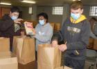 Left to right: Landon DeSmet, Chloe Davis, Sawyer DeSmet and Jeren Rost (background) were among the Area Mission Trip and National Honor Society students that packed 150 "Santa Bags" with food and beverages in the Hope Lutheran Church basement before distributing them to needy families in a drive-thru event at the Hope Lutheran parking lot last Thursday. 