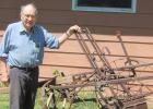 Omer Laleman stands by the horse-drawn cultivator he discovered recently and is fixing up at his home in Minneota. The cultivator, which was pulled by two horses, is similar to one Laleman used when he was a young farmer. 