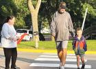 Elementary Principal Jen Mahan-Deitte holds up traffic as a student and his father cross the street. 