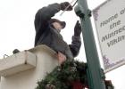 Maintenance worker Tim DeVlaeminck put the wreaths for Christmas decorations on lightpoles in the community on Tuesday, in preparation for the holidays. 
